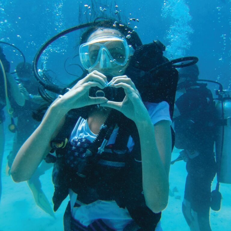 Underwater shoot of a woman diving with scuba and showing love signal